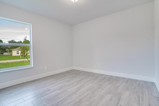 unfurnished room with light wood-style flooring and baseboards