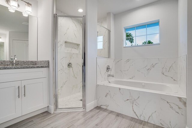 full bathroom with a bath, a marble finish shower, and vanity