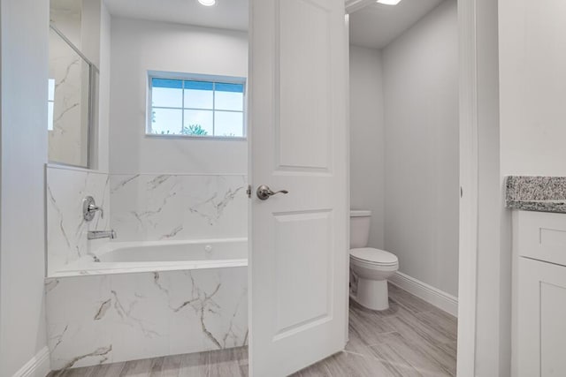 full bathroom featuring toilet, a bath, vanity, and baseboards