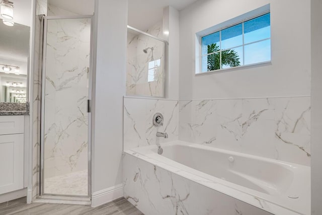 full bathroom featuring wood finished floors, vanity, a bath, and a marble finish shower
