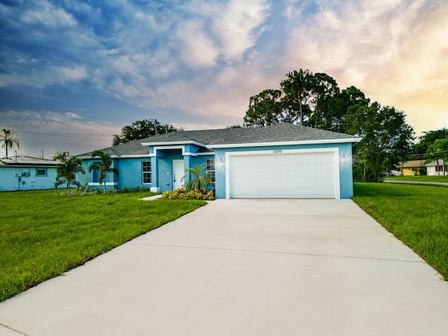 view of front facade with a garage, stucco siding, driveway, and a yard
