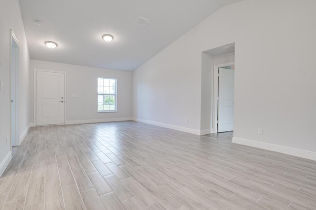 unfurnished room with light wood finished floors, vaulted ceiling, and baseboards