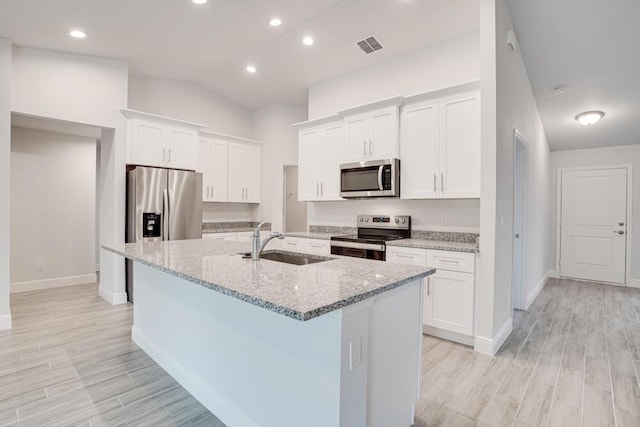 kitchen with a sink, light wood-style floors, stainless steel appliances, and a center island with sink