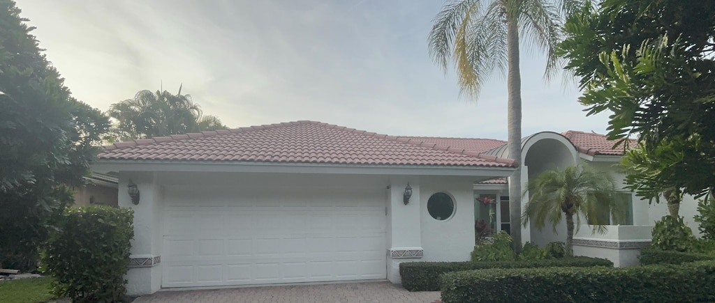 6015 Buena Vista Ct, Boca Raton, FL 33433 - mediterranean / spanish home featuring a tiled roof, an attached garage, decorative driveway, and stucco siding