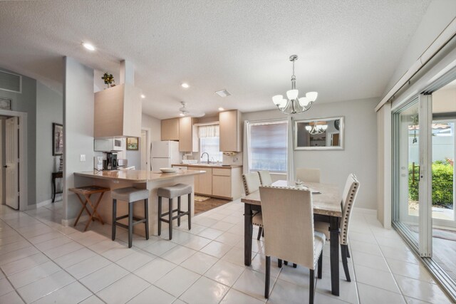 dining space with an inviting chandelier, visible vents, baseboards, a textured ceiling, and light tile patterned floors