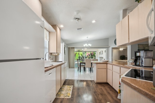 kitchen with visible vents, a peninsula, light brown cabinetry, and white appliances