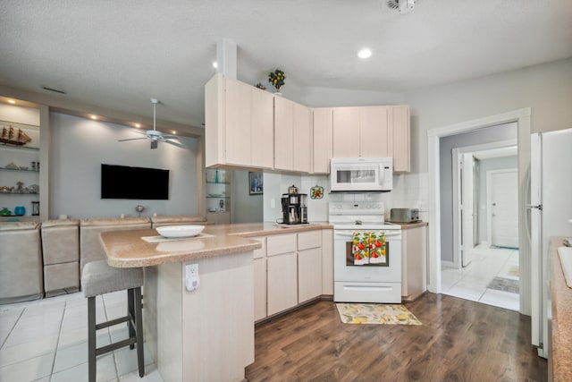 kitchen with a peninsula, white appliances, open floor plan, light countertops, and a ceiling fan