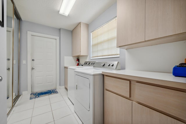 laundry room featuring light tile patterned floors, a textured ceiling, cabinet space, and washing machine and clothes dryer