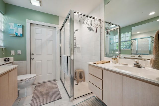 bathroom with tile walls, a shower stall, vanity, tile patterned floors, and toilet