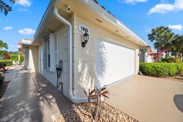 view of side of property featuring concrete driveway, stucco siding, and a garage