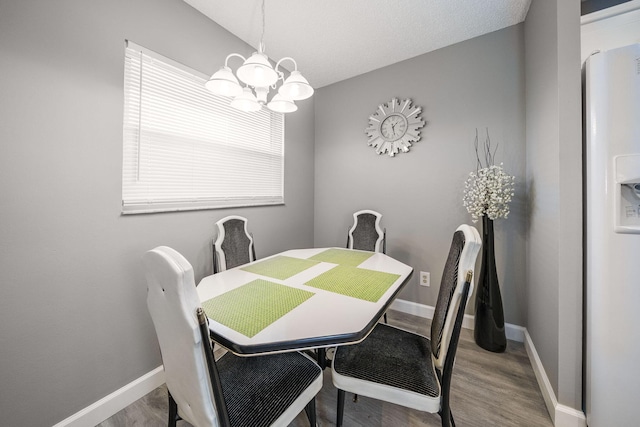 dining space featuring baseboards, wood finished floors, and a chandelier