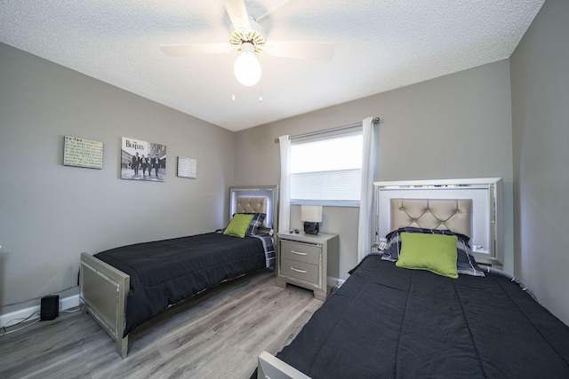 bedroom with baseboards, a ceiling fan, light wood-style flooring, and a textured ceiling