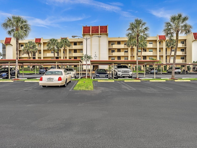 view of building exterior featuring covered and uncovered parking