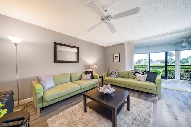 living area with baseboards, a ceiling fan, and wood finished floors