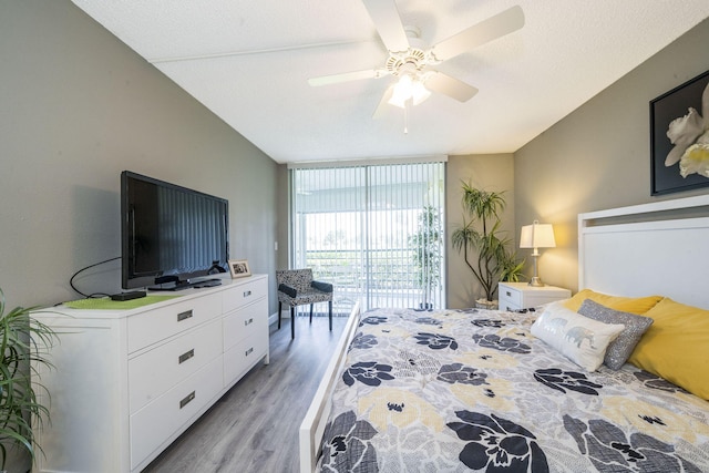 bedroom with access to outside, ceiling fan, a wall of windows, and light wood finished floors