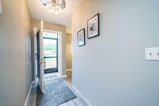 interior space with a textured ceiling, baseboards, a chandelier, and wood finished floors