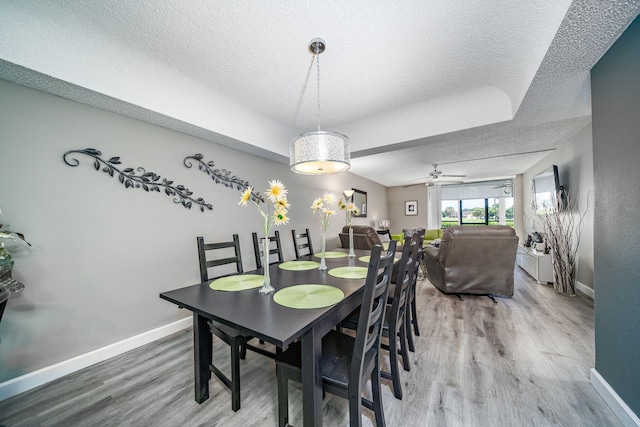 dining area with baseboards, a textured ceiling, and wood finished floors