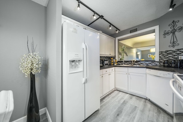 kitchen featuring white appliances, backsplash, dark countertops, and visible vents