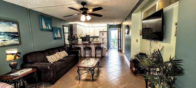 living area featuring tile patterned floors, a textured ceiling, and ceiling fan