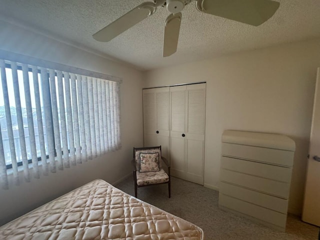 bedroom with a textured ceiling, ceiling fan, carpet flooring, and a closet