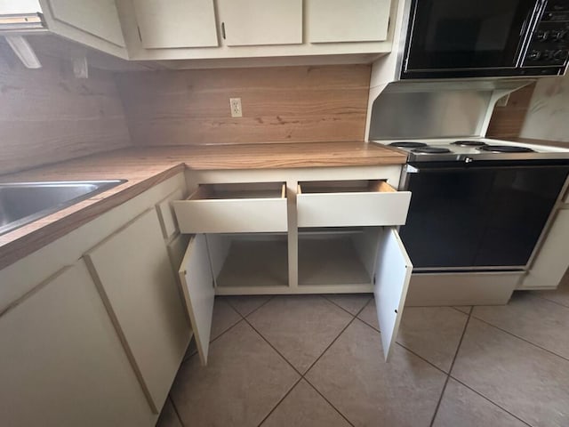 kitchen featuring electric range, light countertops, white cabinets, and light tile patterned floors