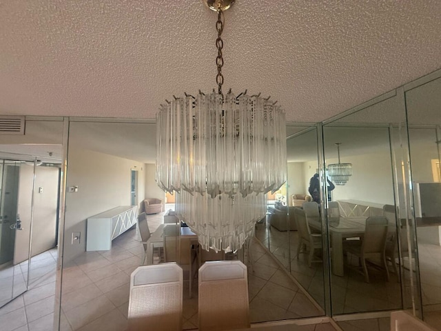 dining space with visible vents, light tile patterned floors, an inviting chandelier, and a textured ceiling