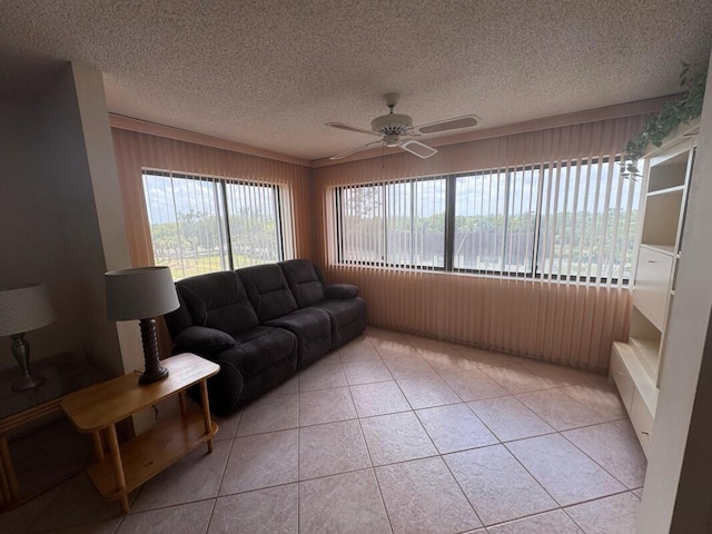 living room with wood walls, light tile patterned floors, ceiling fan, and a textured ceiling