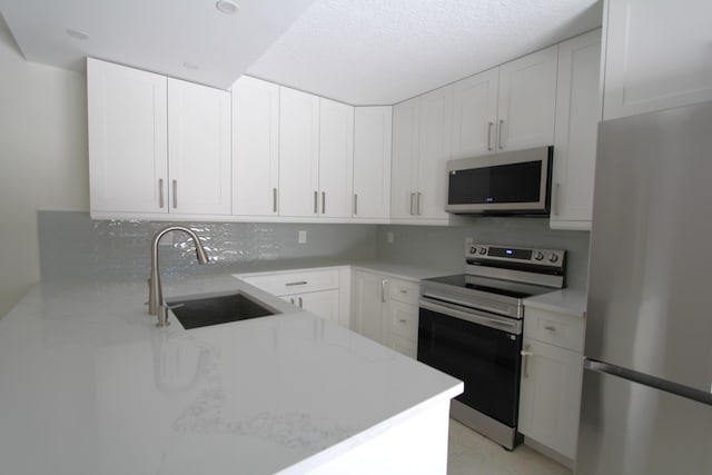 404 Live Oak Ln, Boynton Beach, FL 33436 - kitchen with decorative backsplash, white cabinets, a sink, appliances with stainless steel finishes, and light stone countertops