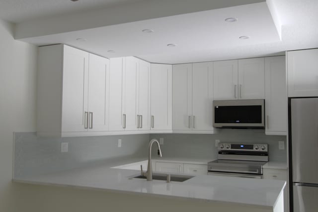 404 Live Oak Ln, Boynton Beach, FL 33436 - kitchen featuring white cabinetry, a sink, appliances with stainless steel finishes, light countertops, and a peninsula