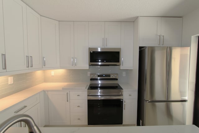 404 Live Oak Ln, Boynton Beach, FL 33436 - kitchen with tasteful backsplash, stainless steel appliances, white cabinets, and a textured ceiling