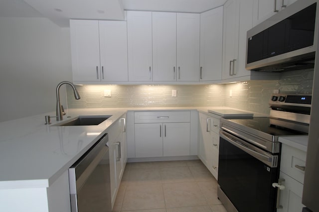 404 Live Oak Ln, Boynton Beach, FL 33436 - kitchen featuring decorative backsplash, appliances with stainless steel finishes, white cabinets, a sink, and light tile patterned flooring