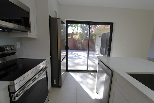 404 Live Oak Ln, Boynton Beach, FL 33436 - kitchen featuring light tile patterned flooring, appliances with stainless steel finishes, light stone countertops, and white cabinetry