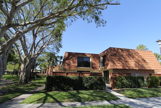 404 Live Oak Ln, Boynton Beach, FL 33436 - view of front of house with brick siding, a front lawn, mansard roof, and a balcony