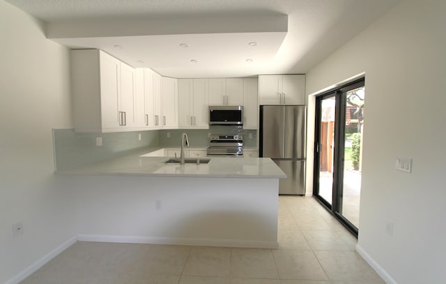 404 Live Oak Ln, Boynton Beach, FL 33436 - kitchen with a sink, decorative backsplash, a peninsula, light countertops, and appliances with stainless steel finishes