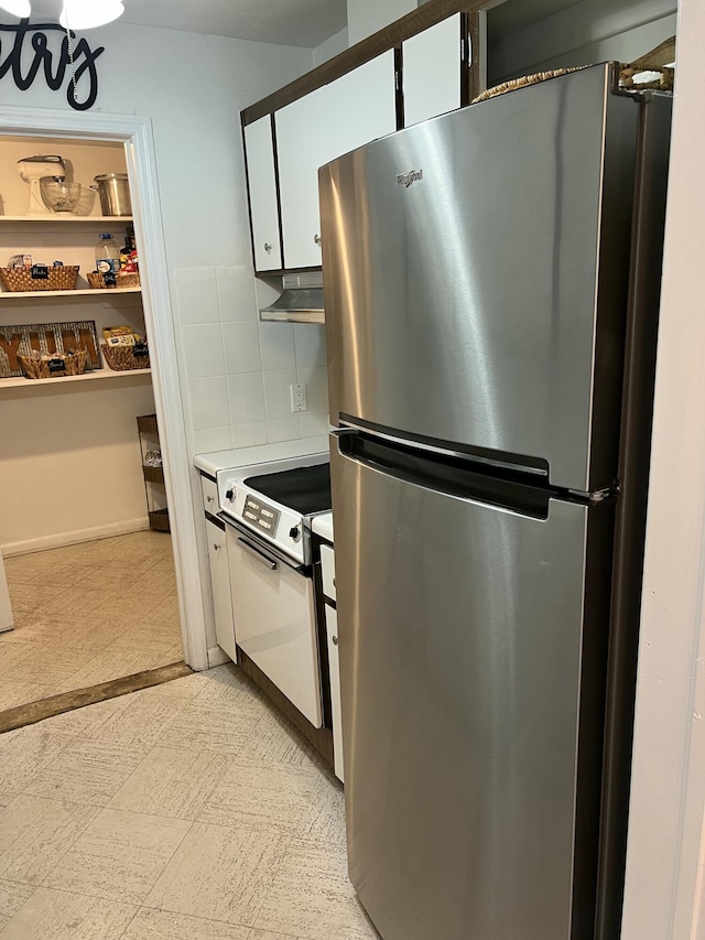 95 E E Ct, Royal Palm Beach, FL 33411 - kitchen with freestanding refrigerator, decorative backsplash, white cabinetry, light countertops, and under cabinet range hood