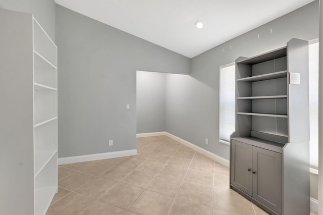 unfurnished room featuring light tile patterned floors, baseboards, and lofted ceiling