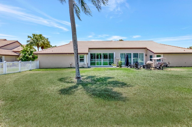 back of property with a yard, a tile roof, a fenced backyard, and stucco siding