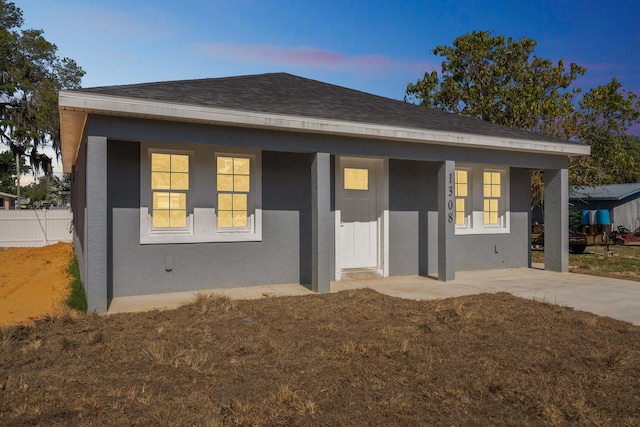 bungalow-style house featuring a shingled roof, fence, a porch, and stucco siding