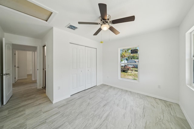 unfurnished bedroom with visible vents, ceiling fan, baseboards, a closet, and attic access