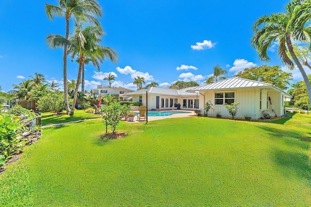 940 Turner Quay, Jupiter, FL 33458 - rear view of property with board and batten siding, an outdoor pool, a standing seam roof, a lawn, and metal roof