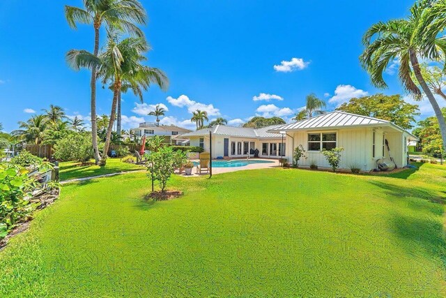 940 Turner Quay, Jupiter, FL 33458 - rear view of property with board and batten siding, an outdoor pool, a standing seam roof, a lawn, and metal roof