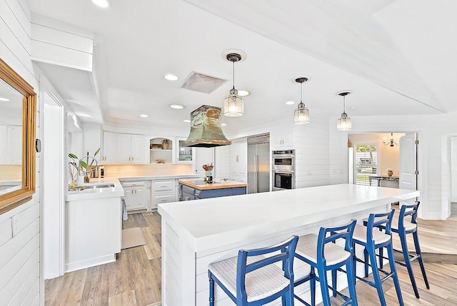 940 Turner Quay, Jupiter, FL 33458 - kitchen with butcher block countertops, stainless steel appliances, island exhaust hood, light wood-type flooring, and a kitchen island