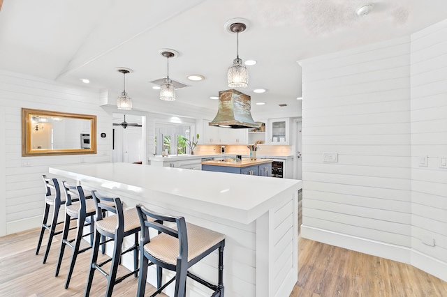 940 Turner Quay, Jupiter, FL 33458 - kitchen with light wood-style floors, a breakfast bar area, beverage cooler, white cabinetry, and a kitchen island