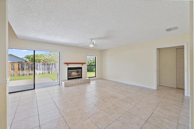 6089 Adams St, Jupiter, FL 33458 - unfurnished living room with a textured ceiling, visible vents, light tile patterned floors, and a glass covered fireplace