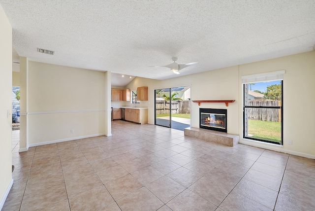 6089 Adams St, Jupiter, FL 33458 - unfurnished living room with a ceiling fan, a textured ceiling, visible vents, light tile patterned flooring, and a fireplace