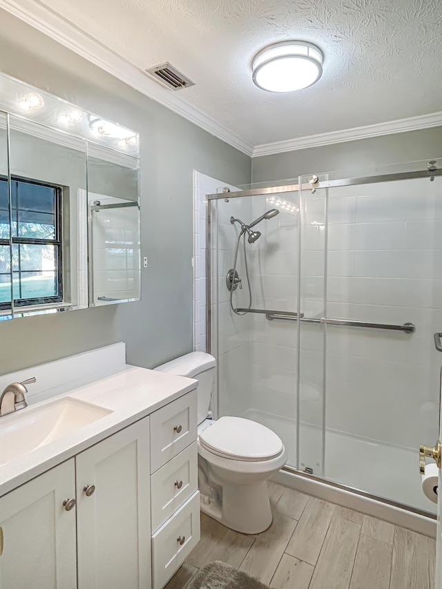 bathroom with wood finished floors, ornamental molding, toilet, visible vents, and a stall shower