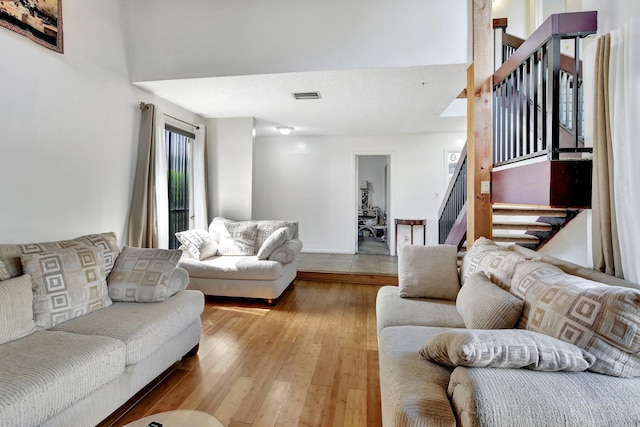 living room with stairs, visible vents, and hardwood / wood-style flooring