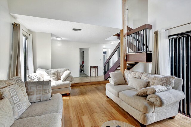 living area featuring stairway, visible vents, wood finished floors, and a towering ceiling