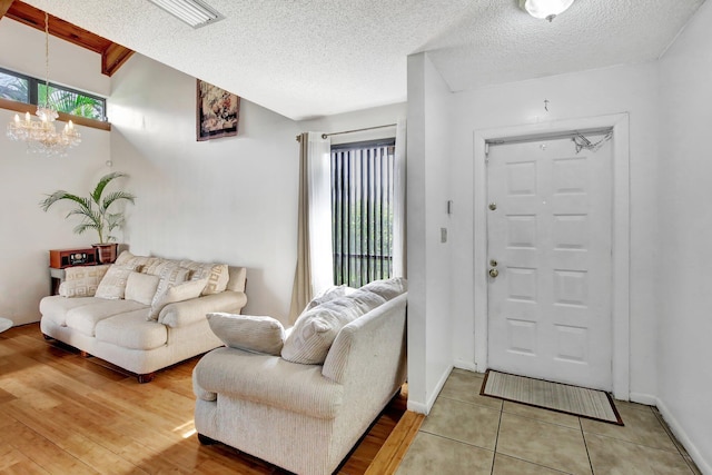 living area featuring a chandelier, baseboards, a textured ceiling, and light tile patterned flooring