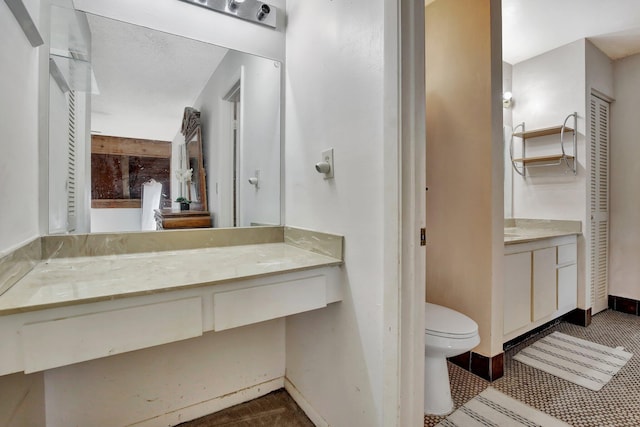 bathroom featuring toilet, vanity, and baseboards